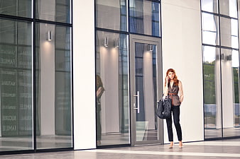 Businesswoman talking on phone outside modern glass office building