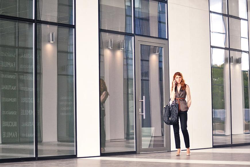 Businesswoman talking on phone outside modern glass office building