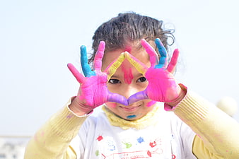 Young girl with colorful Holi powder hands framing face