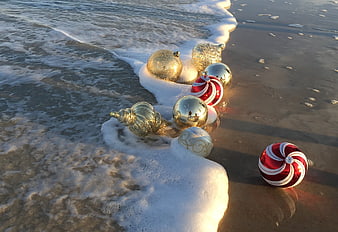 Christmas Ornaments On Wet Sand At The Ocean Shore