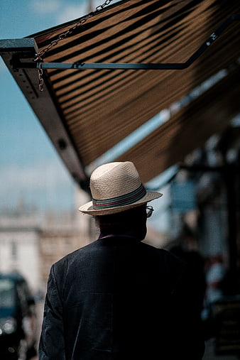 Man in Straw Hat Walking Under Awning