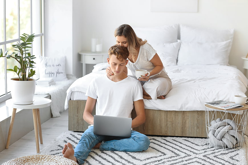Young couple relaxing in bright bedroom with laptop