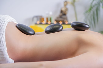 Hot stone massage therapy on back with spa background