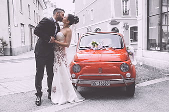 Bride and Groom Kissing Beside Red Vintage Fiat Car
