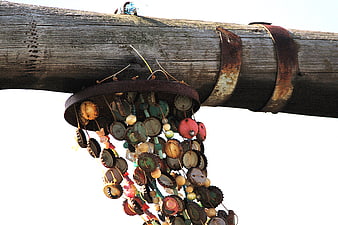Rustic DIY wind chime made of bottle caps hanging from a weathered wooden pole