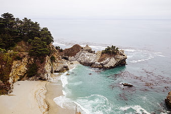 Aerial View of Secluded Coastal Beach with Cliffside Waterfall