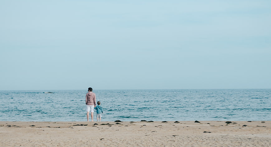 Father and Son Holding Hands Looking at Ocean Horizon
