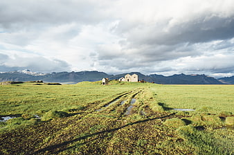 Icelandic landscape with grassy field, mountains, and cloudy sky