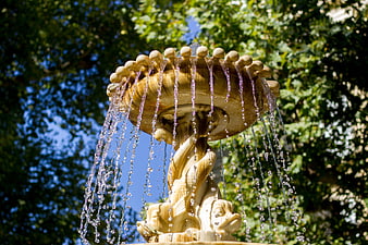 Ornate stone fountain with water jets in a sunny garden