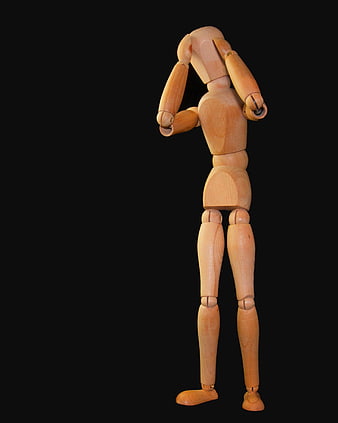 Wooden artist mannequin with hands on head against black background