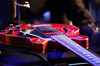 Red Electric Guitar Close-Up On Stage With Dramatic Blue Lighting