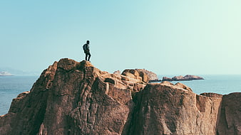 Hiker standing on rocky cliff overlooking the ocean