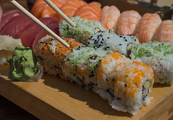 Assorted sushi platter with chopsticks and wasabi on wooden board