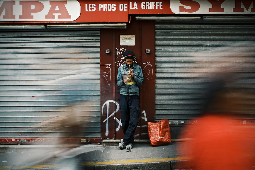 Street musician playing saxophone in front of closed shop