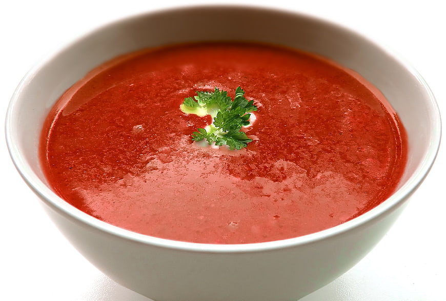 Creamy tomato soup in white bowl with parsley garnish