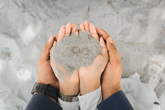 Couple Hands Holding Sand with Wedding Rings