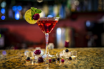 Red cocktail with lemon and berries on bar counter