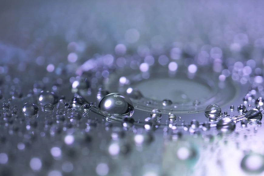 Macro water droplets and ripples on a reflective surface