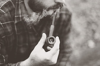 Close-up of bearded man smoking a pipe in black and white