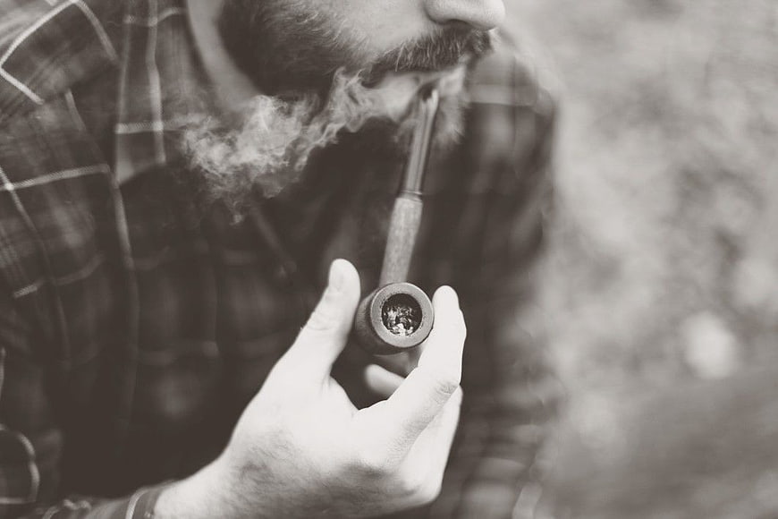 Close-up of bearded man smoking a pipe in black and white