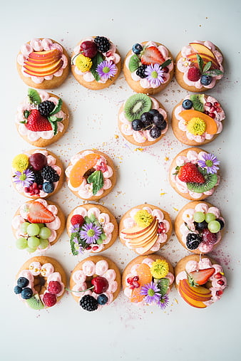 Overhead view of assorted fruit tarts with pink frosting