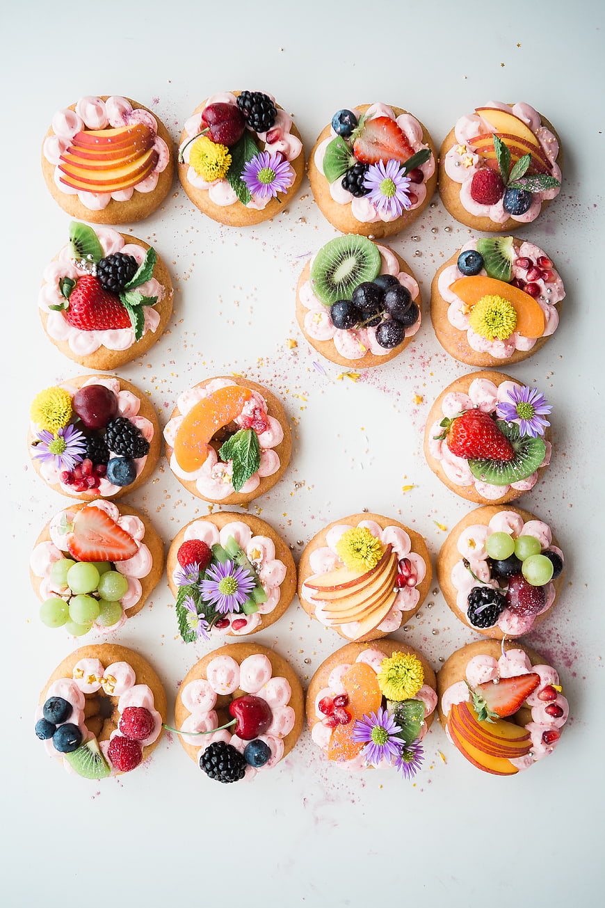 Overhead view of assorted fruit tarts with pink frosting
