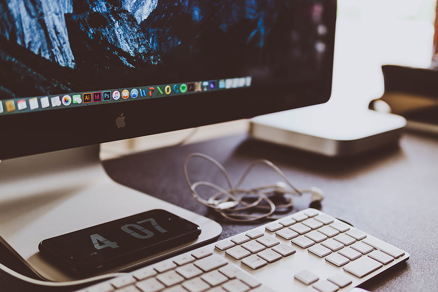 Modern workspace with iMac, smartphone, and keyboard on desk