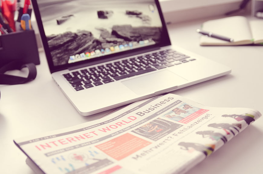 Laptop and Business Newspaper on White Office Desk