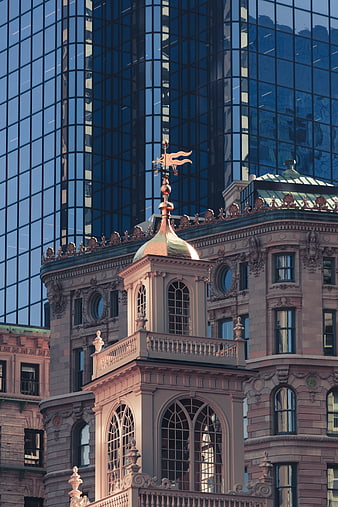 Ornate Historic Building Tower with Weathervane Against Modern Glass Skyscraper