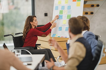 Woman in wheelchair leading business meeting with whiteboard