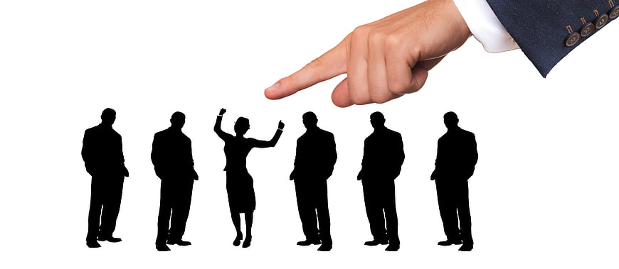 Hand pointing at selected businesswoman silhouette from group