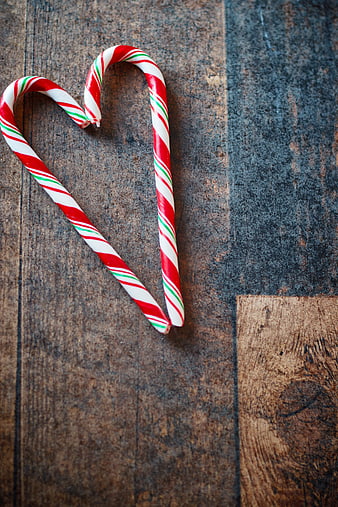 Candy Canes Forming Heart Shape on Rustic Wood