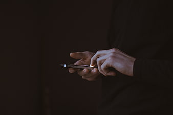 Close-up of hands typing on smartphone in dark setting