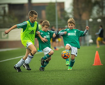 Young boys playing soccer training drill on green field