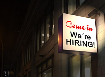 Illuminated We're Hiring Sign on Building at Night