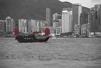 Traditional Chinese Junk Boat With Red Sails In Hong Kong Harbor