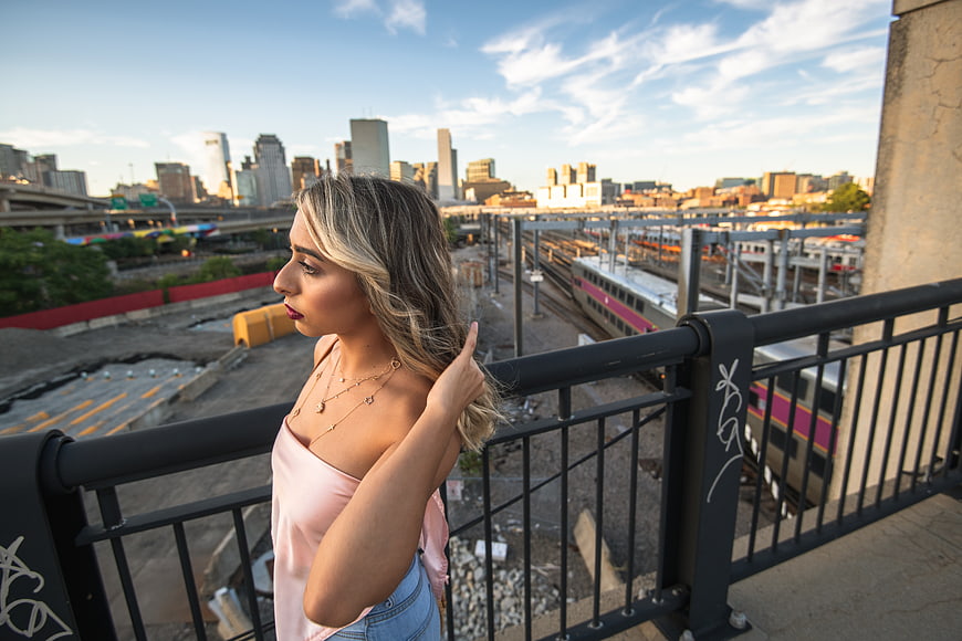 Blonde Woman in Pink Top on Urban Bridge with City Skyline