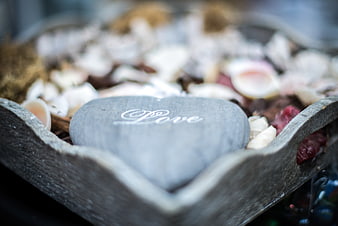 Heart-shaped stone engraved with love in wooden bowl