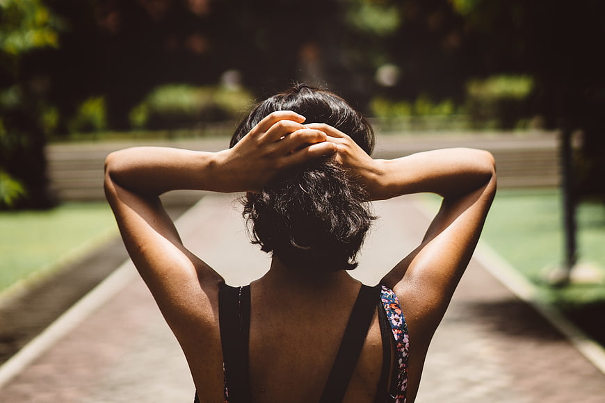 Woman with hands behind head on park path