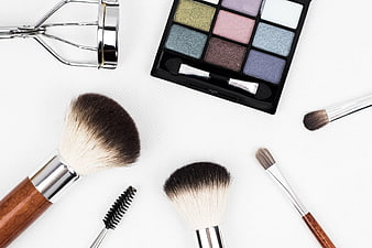 Flat lay of makeup brushes, eyeshadow palette, and eyelash curler