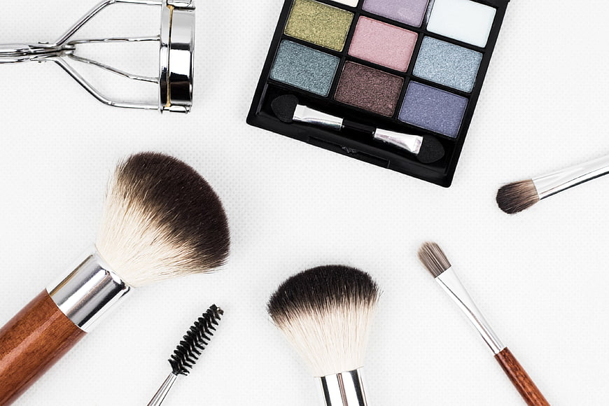 Flat lay of makeup brushes, eyeshadow palette, and eyelash curler