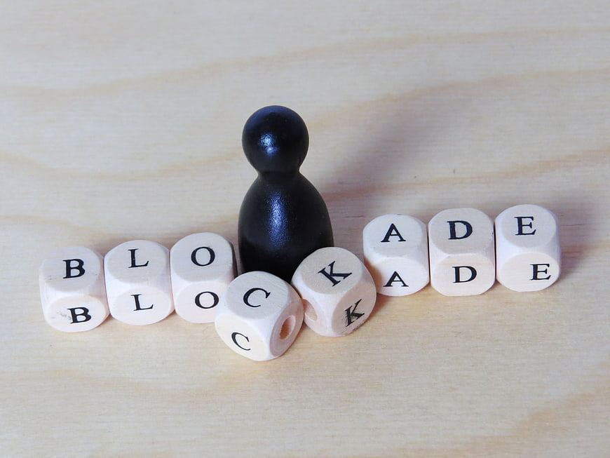 Black Figure Blocking White Dice With Blockade Text