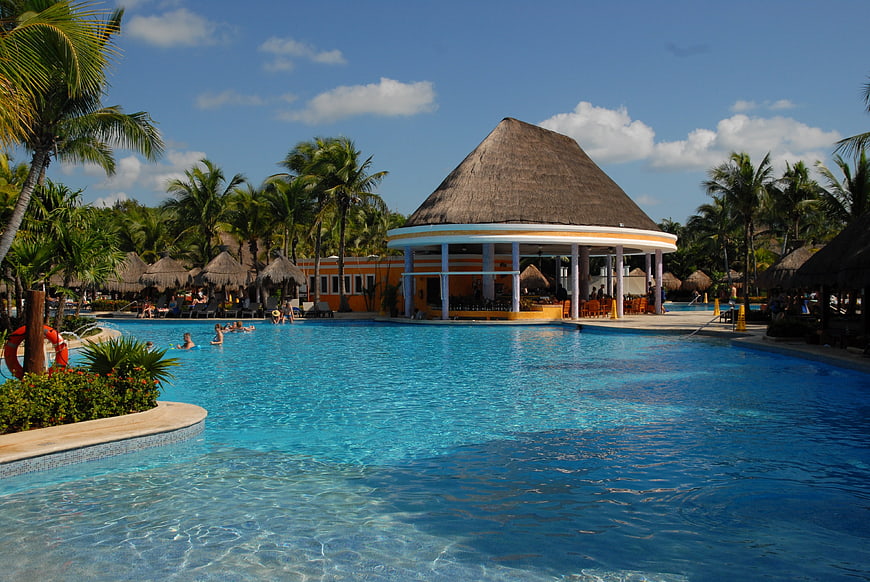 Tropical Resort Swimming Pool With Thatched Pavilion And Palm Trees