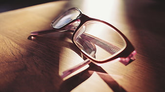 Close-up of eyeglasses on wooden table with sunlight