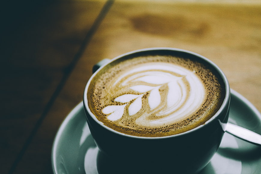 Close-up of latte art in a ceramic cup on a wooden table