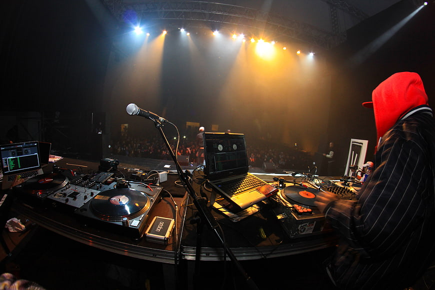 DJ performing at a live concert with turntables and laptops