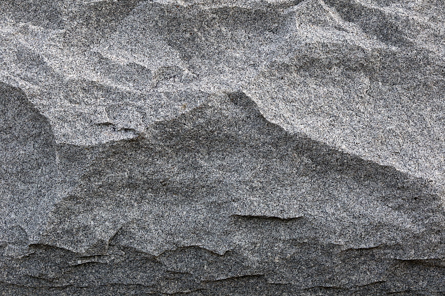 Close-up texture of rough grey granite rock surface