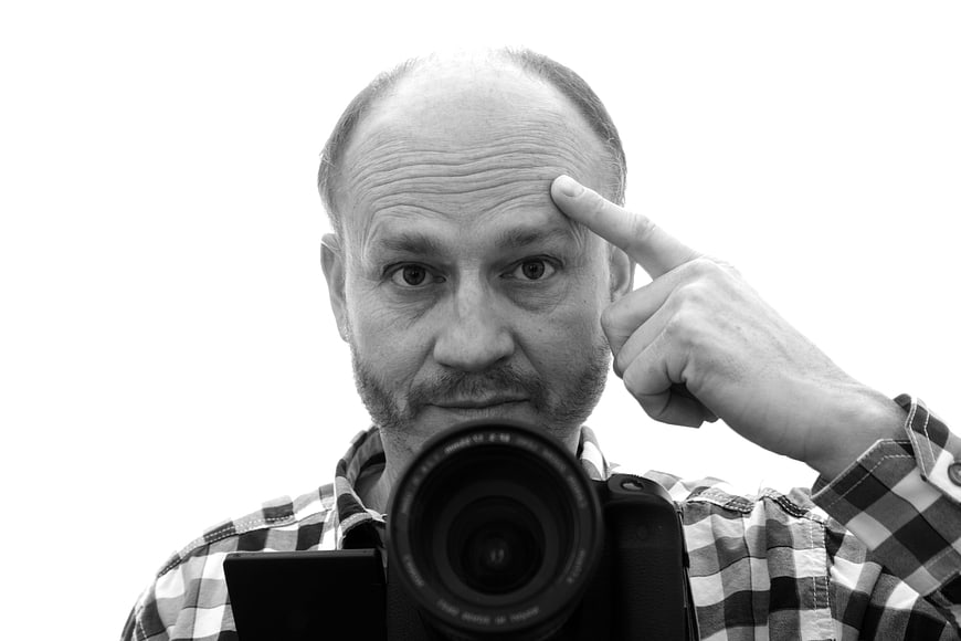 Black and white portrait of a male photographer holding a camera