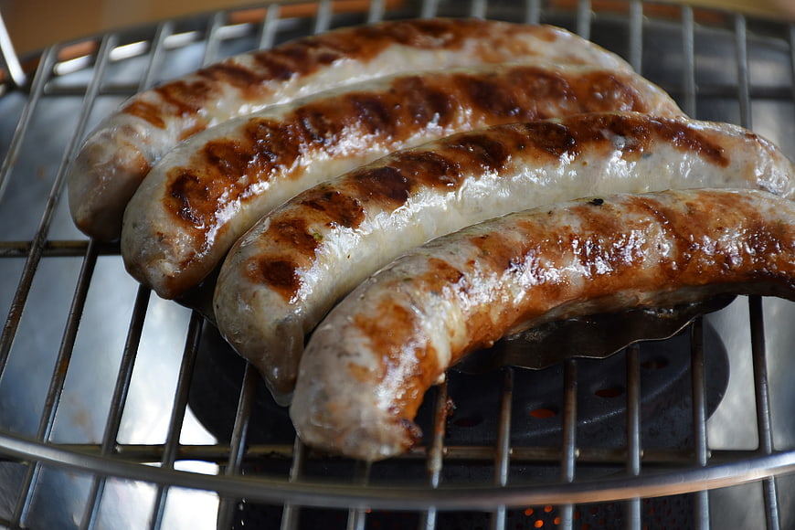 Grilled sausages on a metal barbecue grill grate