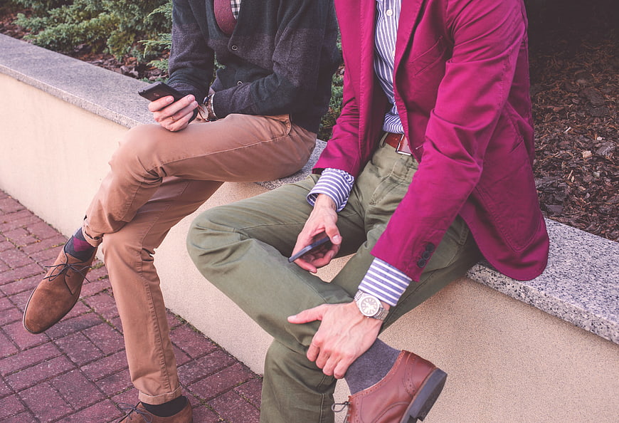 Two Men in Smart Casual Fashion Sitting on a Wall